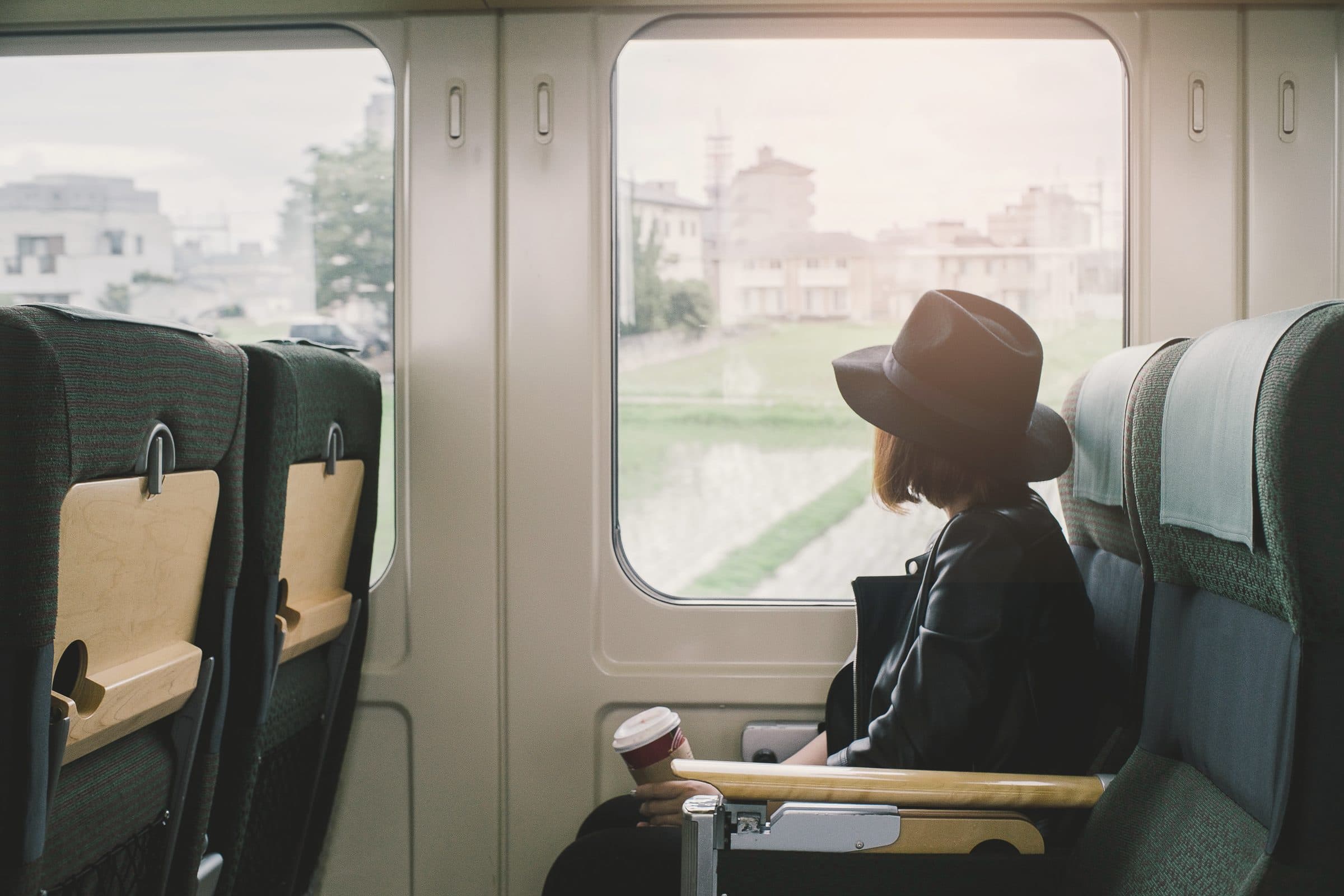 A traveler in a window seat, the town passing outside the glass